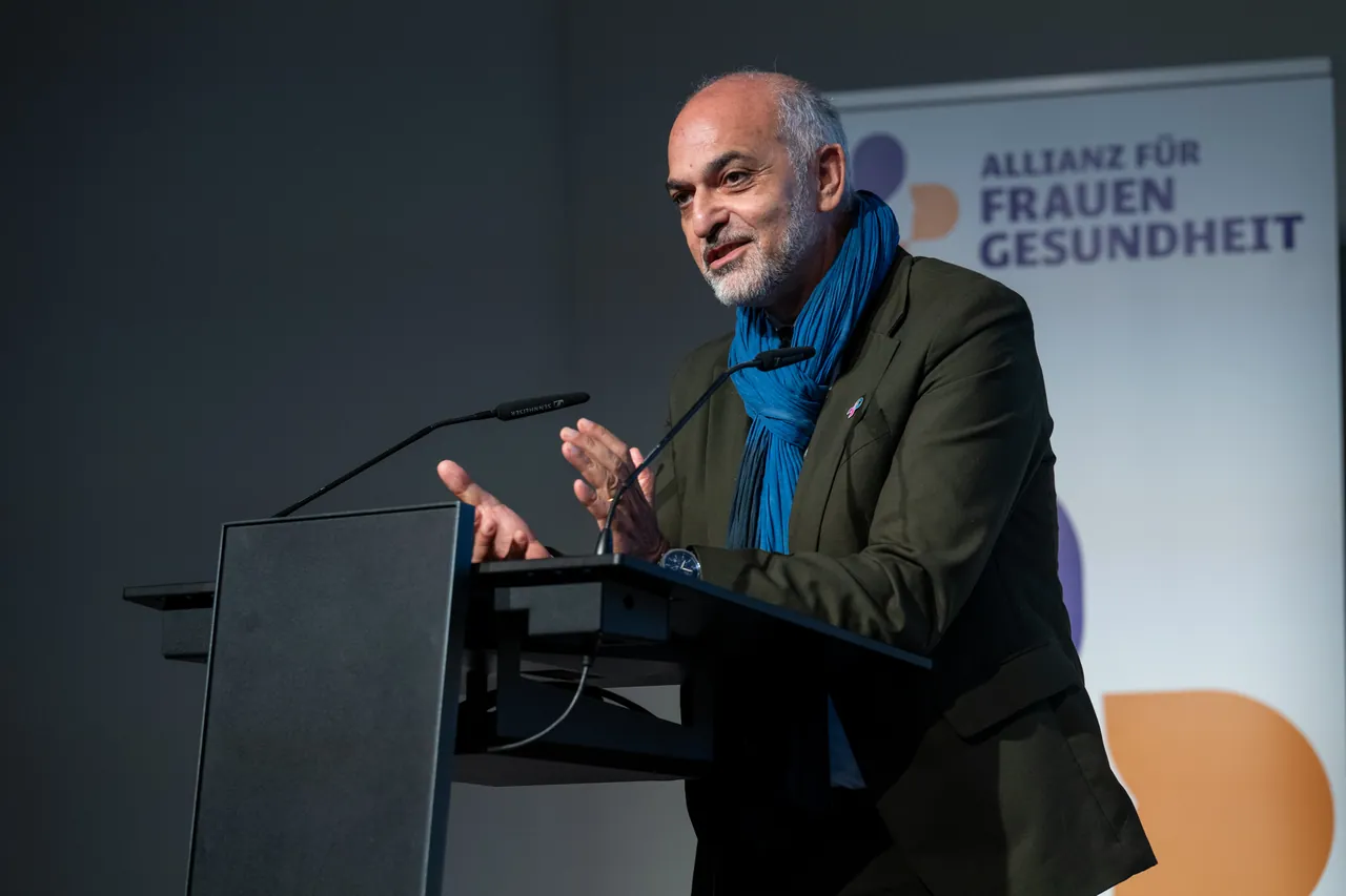 Redner mit blauem Schal spricht am Pult