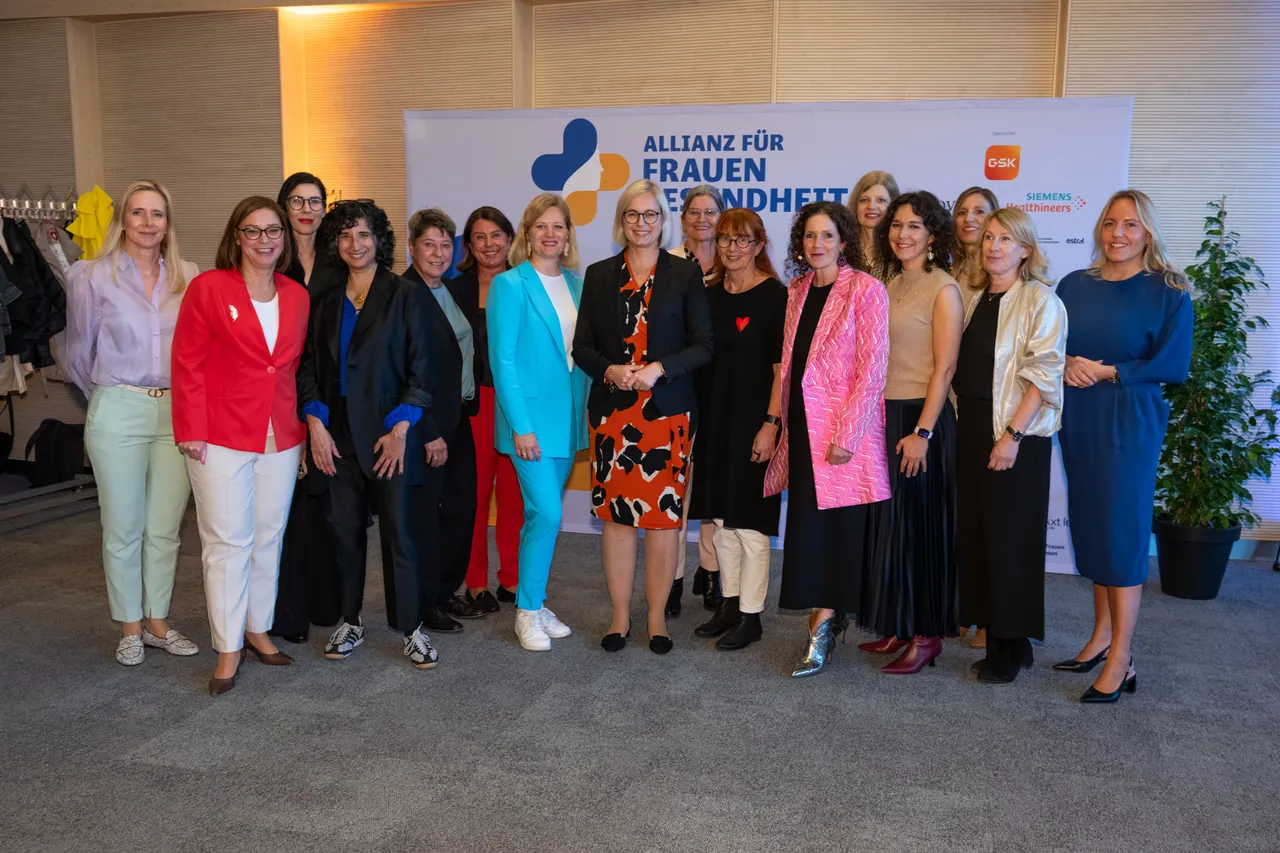 Gruppenfoto zahlreicher Frauen vor einer Wand mit dem Logo der Allianz für Frauengesundheit